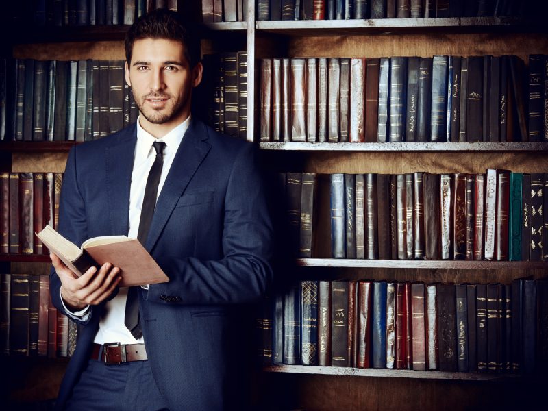 Respectable young man in the old library. Classic vintage interior.